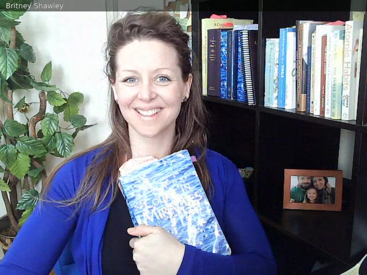 Britney Shawley smiling and holding her Sparkly Edition of A Course in Miracles